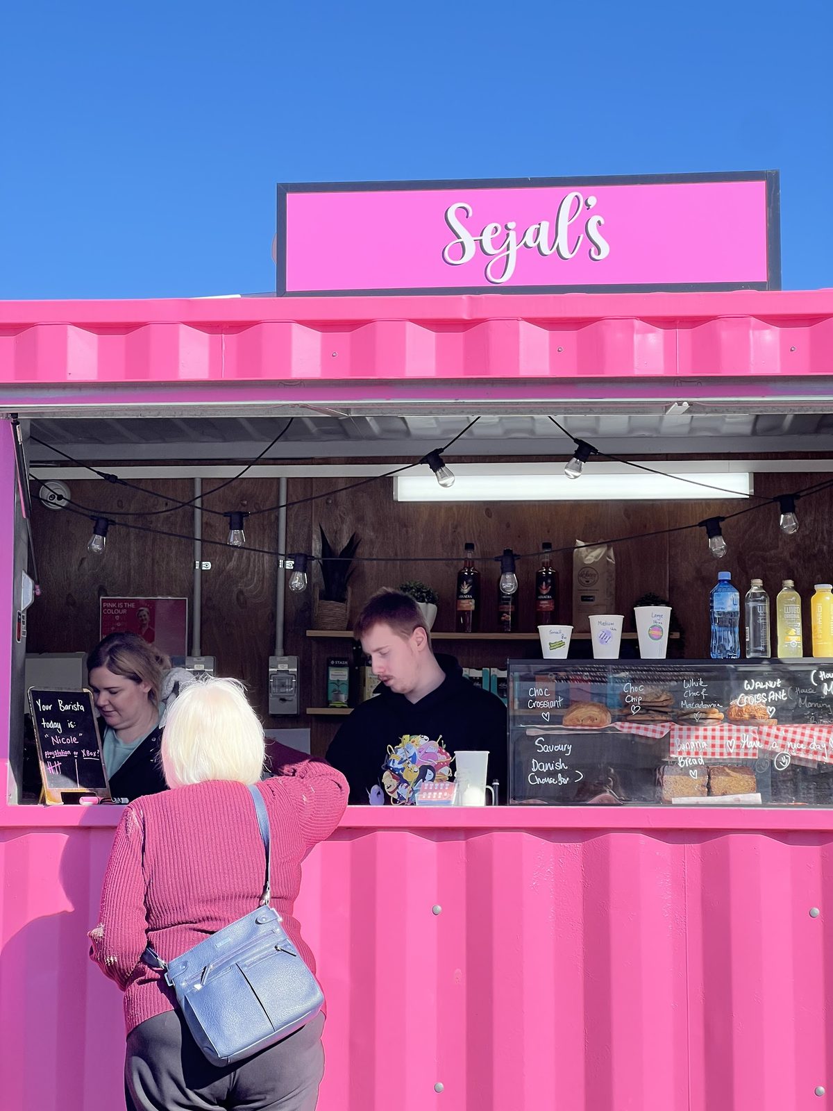 The hot pink Sejal's container on Hobart Road, with customers being served at the window